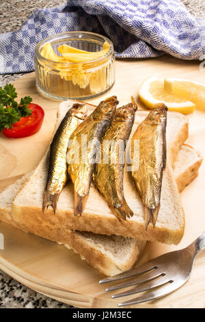 Geräucherte Sprotten auf Toast Brot mit Tomaten und Zitrone Stockfoto