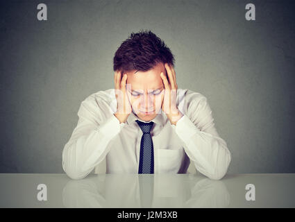 Verzweifelte traurige junger Geschäftsmann stützte sich auf einen Schreibtisch Stockfoto