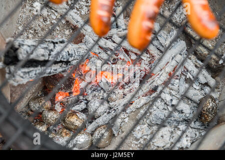 Kochen mit Würstchen auf einem alten Feuer Topf mit Ofenkartoffel Stockfoto