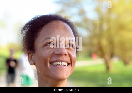 Seitenansicht einer jungen afrikanischen Frau lächelnd, während sie in den Himmel sucht Stockfoto
