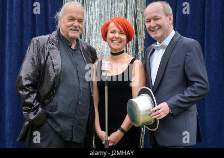 Drei lebhafte Darsteller auf der Bühne feiern vor ein Mikrofon mit einer temperamentvollen rothaarigen Frau und zwei Herren mit Top-Hats, lachen und joki Stockfoto