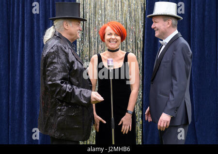 Drei lebhafte Darsteller auf der Bühne feiern vor ein Mikrofon mit einer temperamentvollen rothaarigen Frau und zwei Herren mit Top-Hats, lachen und joki Stockfoto