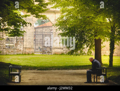 Stra, Italien, Alter 25. April 2017 - Mann sitzt in Einsamkeit auf einem Park Banch im Schatten der Bäume Stockfoto