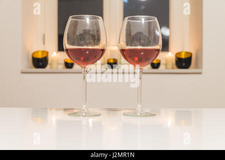 Zwei Gläser mit Rotwein auf weißen Tisch mit weißem Hintergrund und Fenster Stockfoto