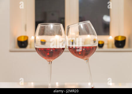Zwei Gläser mit Rotwein auf weißen Tisch mit weißem Hintergrund und Fenster Stockfoto