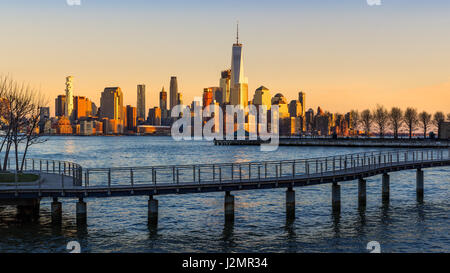 New York City-Financial District Wolkenkratzer bei Sonnenuntergang vom Hudson River. Lower Manhattan Skyline und Fußgängerbrücke aus New Jersey Stockfoto
