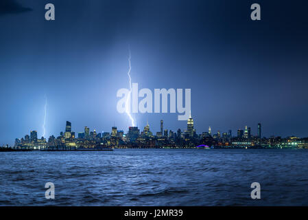 Blitze schlagen New York Wolkenkratzer in der Nacht. Stürmischer Himmel über Midtown West Manhattan vom Hudson River Stockfoto