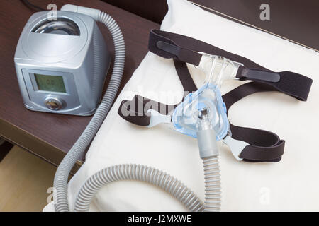 Schlaf-Apnoe-CPAP-Kopfbedeckungen-Maske und Schlauch auf weißen Kissen Anfügen an CPAP-Gerät für Menschen mit Schlafapnoe oder Schlafstörungen Stockfoto