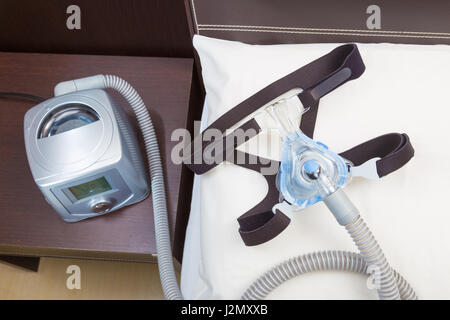 Schlaf-Apnoe-CPAP-Kopfbedeckungen-Maske und Schlauch auf weißen Kissen Anfügen an CPAP-Gerät für Menschen mit Schlafapnoe oder Schlafstörungen Stockfoto