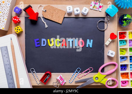 Kleine Tafel mit verschiedenen stationären mit Bildung Word in der Mitte, auf Holz Hintergrund umgeben Stockfoto