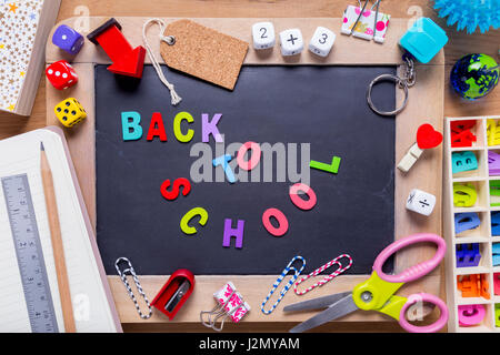 Kleine Tafel mit verschiedenen stationären mit Back To School-Wörter in der Mitte, auf Holz Hintergrund umgeben Stockfoto