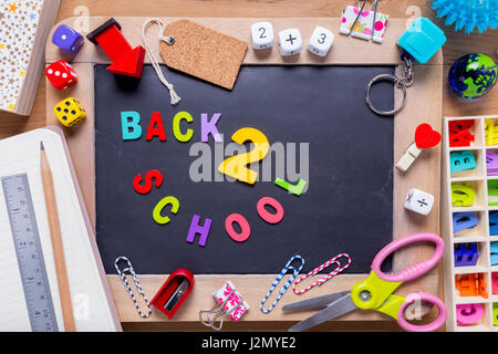 Kleine Tafel mit verschiedenen stationären mit Back 2 School Wörter in der Mitte, alle auf Holz Hintergrund umgeben Stockfoto