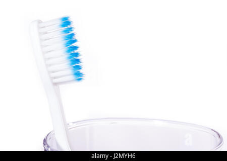 Zahnbürste mit blauen Farbindikator am Ende des dünnen Borsten Tipps Verlegung auf Klarglas-Cup gegen den weißen Hintergrund, selektiven Fokus