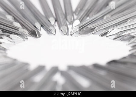 Stahlbeton Nägel zeigen die Spitzen in Richtung leeren weißen Raum für Text in der Mitte des weißen Hintergrundes, selektiven Fokus mit geringer Tiefe von Stockfoto