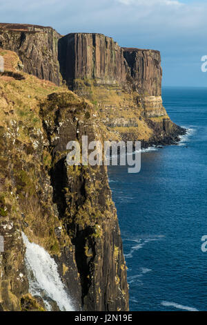 Mealt Wasserfall mit Kilt Rock im Hintergrund. Dies ist eine dramatische Wasserfall erstellt aus dem Abfluss des Loch Mealt, die mündet direkt in die Stockfoto