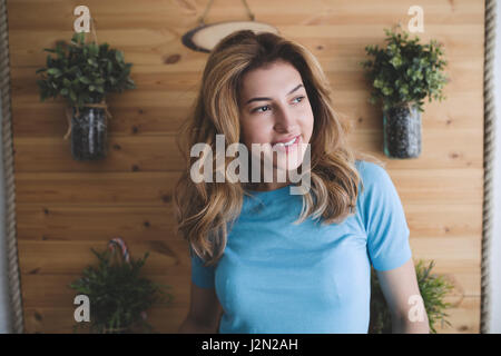 Schöne blonde Frau posiert und lächelnd zu Hause Stockfoto