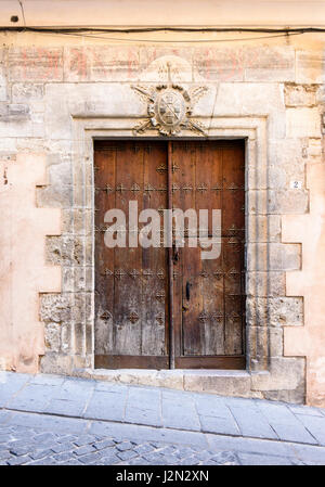 Alte hölzerne doppelte Türen unten ein Wappen auf einem historischen Gebäude in der alten mittelalterlichen Stadt Cuenca, Castilla La Mancha, Spanien Stockfoto