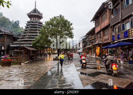 Zhaoxing, Guizhou, China, ein Dong Minderheit Dorf.  Neue Straße mit Läden für Touristen, Drum Tower Links, am frühen Abend, regnerischen Tag. Stockfoto