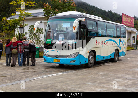 Guizhou, China, zwischen Zhaoxing und Kaili.  Tour-Bus und ausländische Touristen an einer Raststätte am Straßenrand. Stockfoto