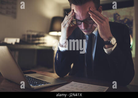 Nachdenklich Geschäftsmann am Schreibtisch und arbeitet mit den Dokumenten in der Nacht. Stockfoto