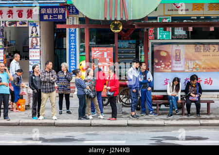 Kaili, Guizhou, China.  Menschen warten auf eine Stadtbus-Haltestelle. Stockfoto