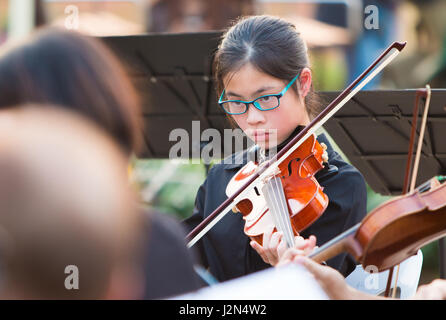 Junge asiatische Geigerin, die bei einem Konzert im freien Stockfoto
