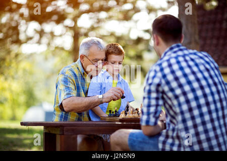 Großvater lehrt seine Enkel Schach in der Natur Stockfoto