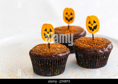 Halloween-Schokoladentörtchen mit orange Dekorationen Stockfoto