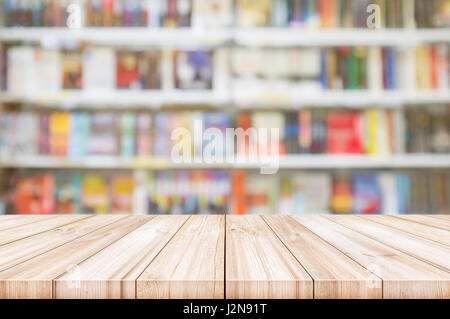 Leere hölzerne Tischplatte mit Unschärfe Bücherregale in Buchhandlung Hintergrund. kann sein Produkt Display verwendet. Stockfoto