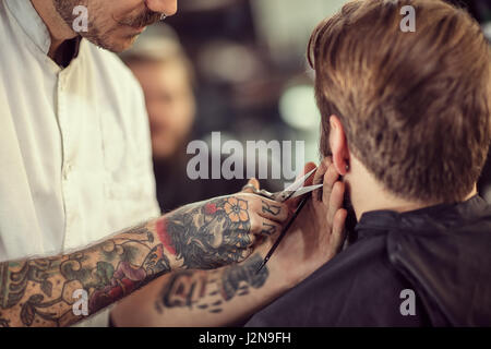 Friseur mit einer Schere schneiden Sie den Bart des Clients hautnah Stockfoto