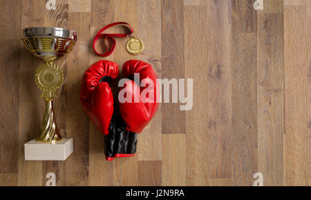 Boxhandschuhe und Trophäen auf Holzbohlen Hintergrund Stockfoto