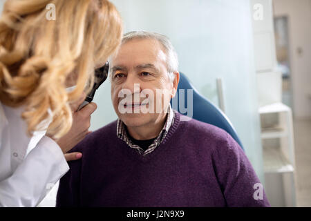 Senior sucht im Instrument zur Überprüfung der Augen beim Augenarzt Stockfoto