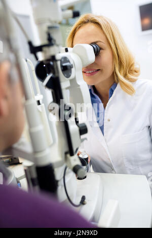 Weibliche blonde Augen Arzt arbeiten mit Geräten und Augen auf männlichen Patienten zu überprüfen Stockfoto
