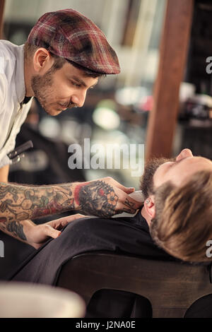 geschickte Barbier rasieren Bart auf client Stockfoto