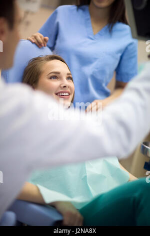 Junge weibliche Kunden am Behandlungsstuhl hören Zahnarzt und freut sich Lösung ihres Problems Zähne Stockfoto