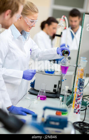 Süße weibliche Chemiker machen Experiment Mischen von Flüssigkeiten im chemischen Labor Stockfoto