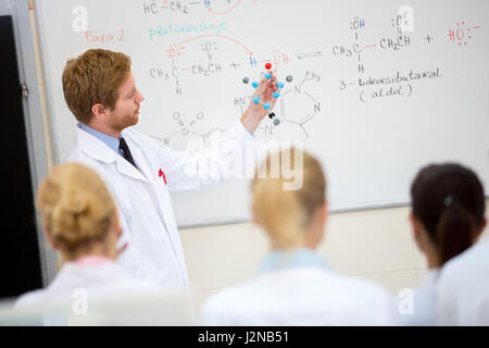 Junge männliche Chemie Lehrer zeigen Molekülmodell Schülern im Klassenzimmer Stockfoto