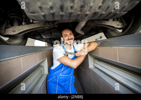 lächelnde Mechaniker unter ein Auto Stockfoto