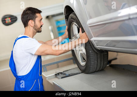 gut aussehend Mechaniker Reifenwechseln in Werkstatt Stockfoto