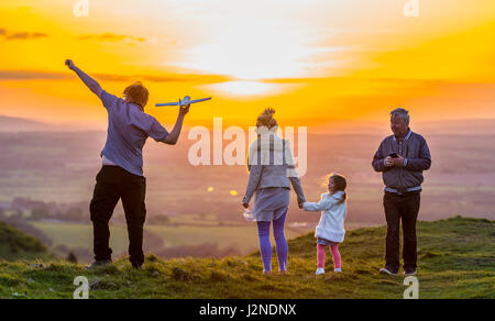 Liebevolle Familie spielen und gute Zeiten auf einem Hügel in der Nähe von Sonnenuntergang in der UK-Landschaft zu genießen. Zeit miteinander zu verbringen. Stockfoto