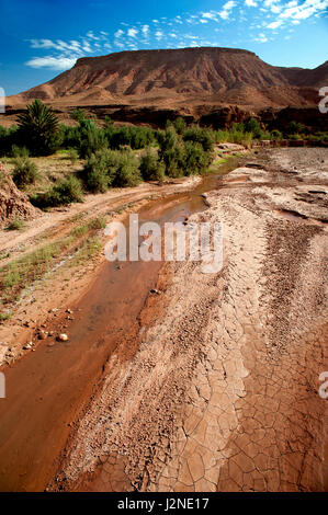 Eine ausgetrocknete Flusstal umgeben von den trockenen Wüstenlandschaft des Atlas-Gebirges in Marokko bei der World Heritage Site von Ait Benhaddou. Stockfoto