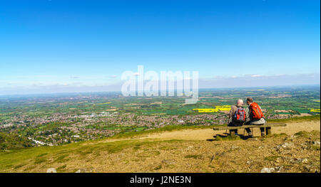 Zwei späte Männer mittleren Alters sitzen auf einer Bank, Blick über den Severn Valley vom oberen Rand der Malvern Hills. Stockfoto