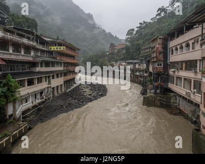 Wulai, Taiwan - 9. Oktober 2016: Landschaft von Gebäuden auf einem nebligen, regnerischen und üppigen Hügel an einem Fluss in Wulai Stockfoto