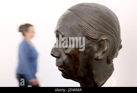 Güstrow, Deutschland. 28. April 2017. Eine Frau geht vorbei an der Skulptur "Selbstbildnis" (Bronze, 1926-1936) von Kaethe Kollwitz (1867-1945) in der Ausstellung "auf der Suche nach der"neue Form". Käthe Kollwitz - druckt Grafik. Skizzen. Skulpturen. "auf der Ausstellung Forum grafischen Kabinett der Ernst Barlach Foundation in Güstrow, Deutschland, 28. April 2017. Die Ausstellung öffnet um den 150. Geburtstag des Künstlers, 30. April 2017. Foto: Bernd Wüstneck/Dpa-Zentralbild/Dpa/Alamy Live News Stockfoto