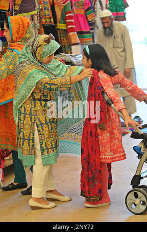 Islamabad, Pakistan. 30. April 2017. Eine Frau versucht eine Kleid auf ihre Tochter am letzten Tag der Fashion Expo 2017 in Islamabad, der Hauptstadt von Pakistan, am 30. April 2017. Über 100 Aussteller nahmen während der zweitägigen Fashion Expo, ihrer Marke zu steigern. Bildnachweis: Saadia Seher/Xinhua/Alamy Live-Nachrichten Stockfoto