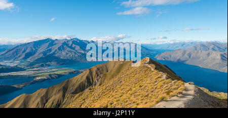 Blick auf Berge und See, Frau springen am Gipfelgrat, Roys Peak, Lake Wanaka, Südalpen, Otago Region Southland Stockfoto