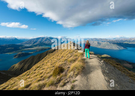 Frau Wandern auf Bergrücken, Blick auf Berge und See, Roys Peak, Lake Wanaka, Südalpen, Otago Region und Southland, Neuseeland Stockfoto
