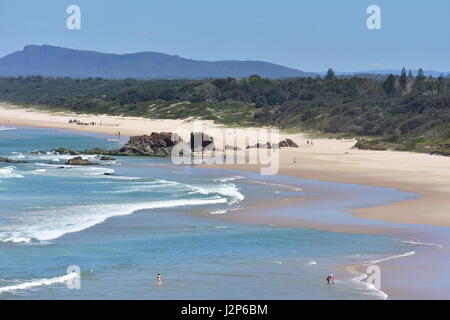 Sandstrand mit weißen ozeanischen Surf südlich von Tacking Point Lighthouse in Port Macquarie mit drei Brüdern in weit im Hintergrund. Stockfoto