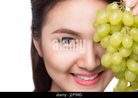 Junge schöne asiatische Frau essen frische Weintrauben isoliert auf weißem Hintergrund Stockfoto