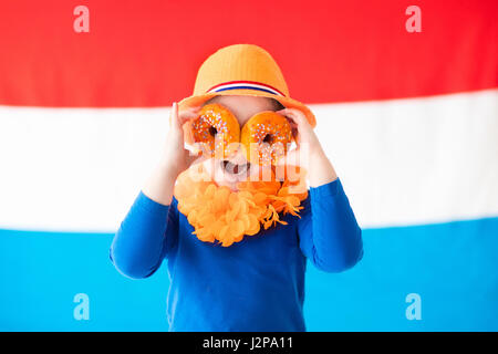 Kleine holländische junge Mädchen tragen Land Symbolen Essen orange Donuts-King-Tag zu feiern. Kinder unterstützen Holland-Sport-Team. Kinder aus den Niederlanden Stockfoto
